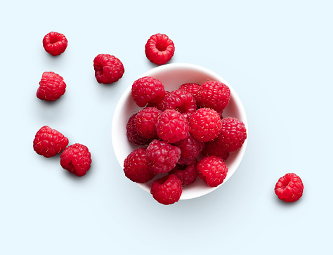 Raspberries in bowl isolated on white background, top view, cutout