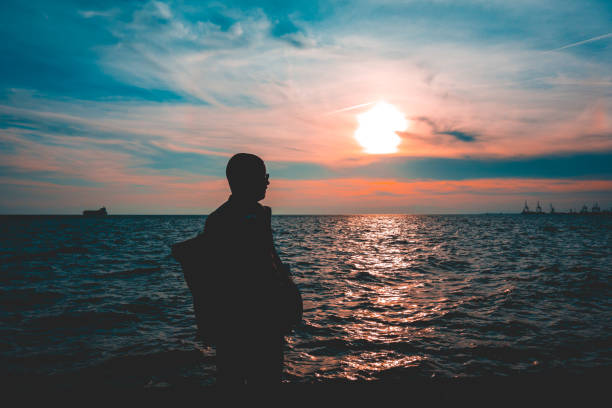 istock Silhouetted man on a seafront promenade at dusk 958841238