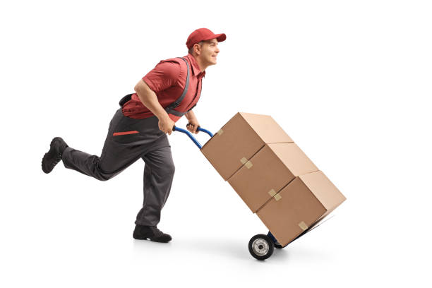 istock Mover running and pushing a hand truck loaded with boxes 958841284