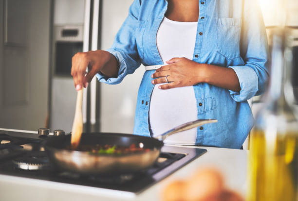 Cooking right up until her last trimester Cropped shot of a pregnant woman preparing a meal on the stove at home last stock pictures, royalty-free photos & images