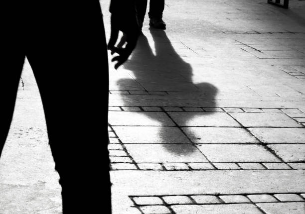 Silhouette shadow of two people Shadow silhouette of two person on city sidewalk in black and white high contrast photos stock pictures, royalty-free photos & images