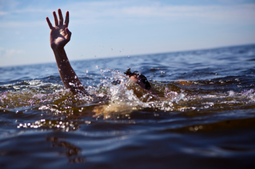 Person drowning in water with hand reached out 