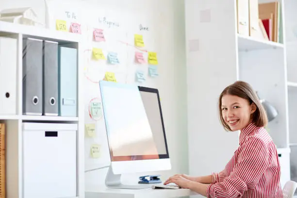 Portrait of smiling businesswoman typing on computer at her workplace at office