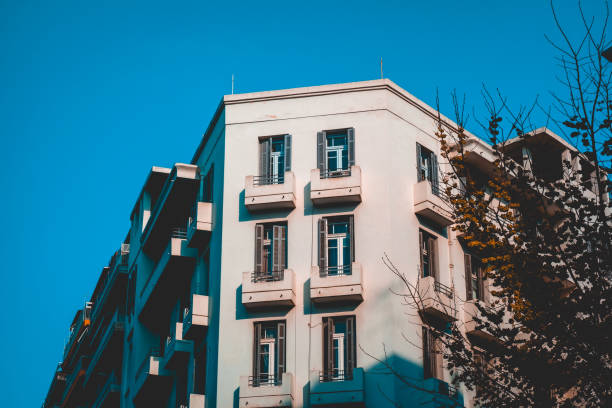 istock white colored corner building with darken tree on the side 958855124