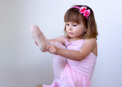 Little ballerina dancer putting on her shoe