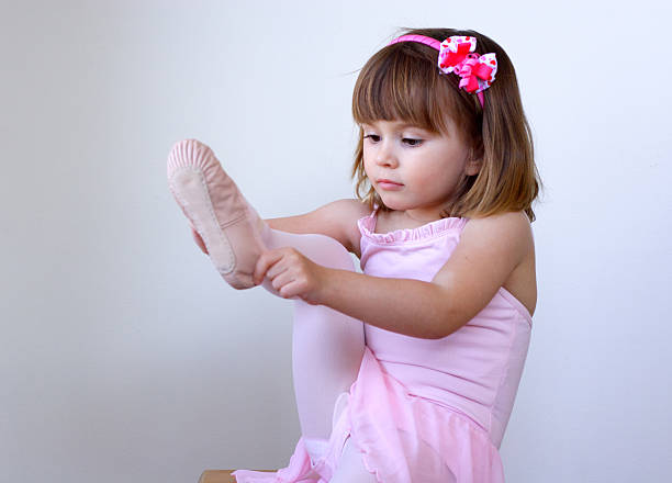 Tiny ballerina putting her slippers on stock photo