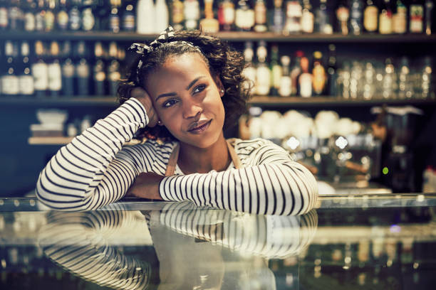 istock Smiling African entrepreneur leaning on her cafe counter thinking 958877734
