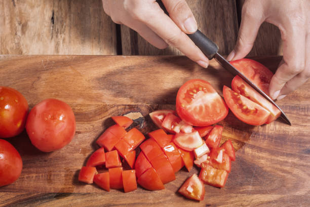 istock Close up Housewife while cutting tomatoes. 958878214