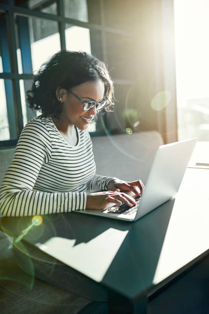 istock Smiling young African woman browsing online with a laptop 958878304