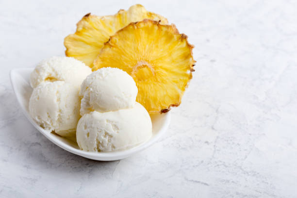 Vanilla ice cream scoops with pineapple chips Vanilla ice cream scoops with pineapple chips on white plate freeze dried ice cream stock pictures, royalty-free photos & images
