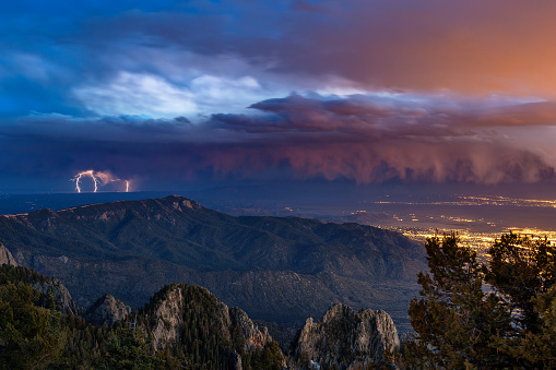 Lightning and dramatic storm clouds from a distant thunderstorm over the city of Alburquerque, New Mexico from the Sandia Mountains.