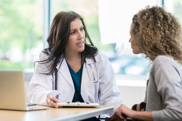 Mature doctor discusses health issues with patient Concerned female doctor discusses a diagnosis with a young female patient. The doctor has a serious expression on her face. clipboard photos stock pictures, royalty-free photos & images