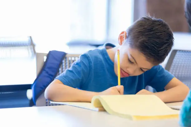 Photo of Little boy concentrates on drawing at school