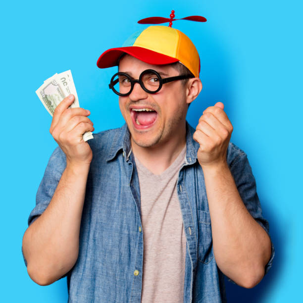 istock Young nerd man with noob hat holding a money 958887684