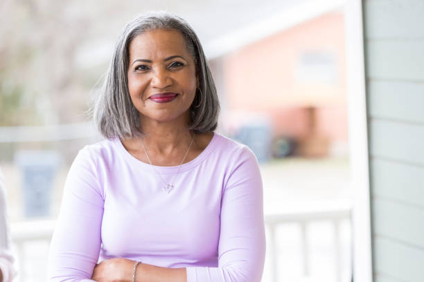 Beautiful senior woman outdoors Beautiful African American senior woman stands confidently on her front porch. She is smiling at the camera. grey hair stock pictures, royalty-free photos & images