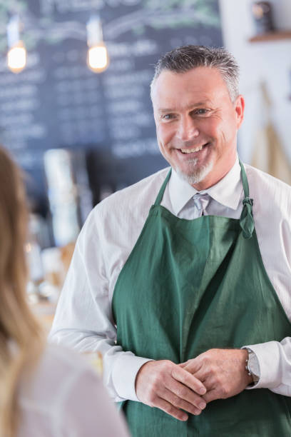 istock Handsome mature waiter helps female customer 958892406