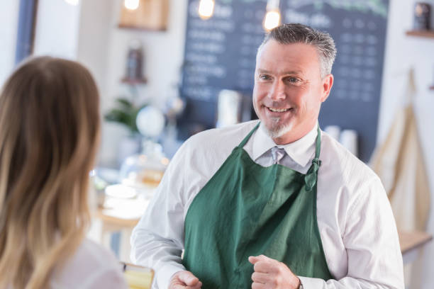 istock Mature coffee shop manager assists customer 958892422