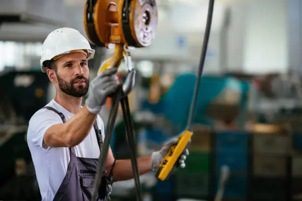 Photo of Worker in factory using lifting beam