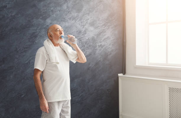 istock Thirsty senior man drinking water from bottle 958893038