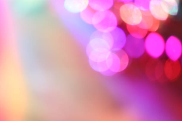 Colorful defocused party lights background.  Hues include: pink, purple, blue, green.