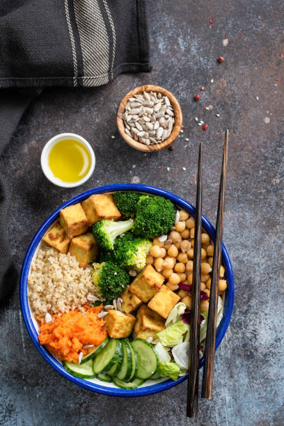 キノア、豆腐、ブロッコリー、サツマイモ、キュウリと鉢の石仏 - rainbow peppercorns ストックフォトと画像