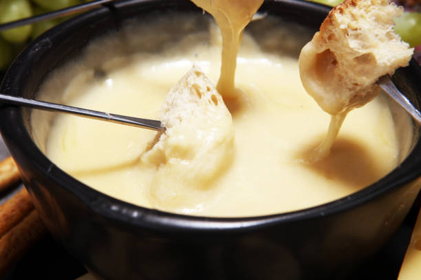 istock Gourmet Swiss fondue dinner on a winter evening with assorted cheeses on a board alongside a heated pot of cheese fondue 958923946