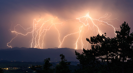 Lightning thunderstorm above mountain range with trees in front viewed from Karst (Slovenia) toward Trnovski gozd (Slovenia).