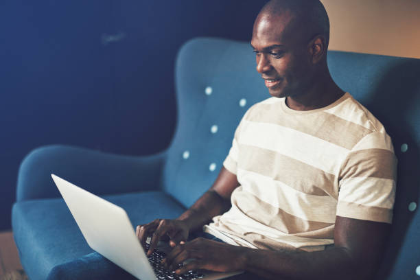 istock Smiling African entrepreneur sitting on a  couch working online 958927368