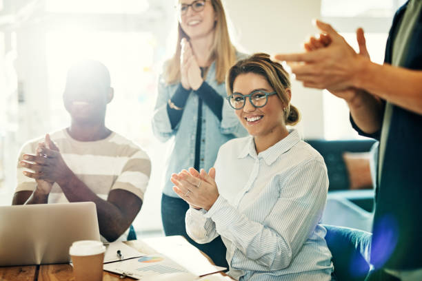 istock Smiling young woman clapping with colleagues in a modern office 958927494