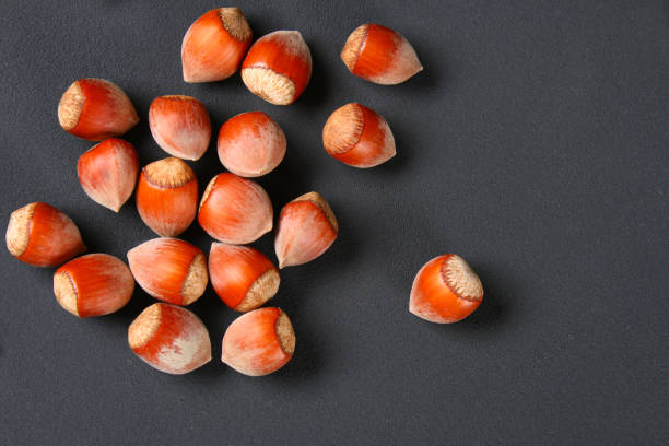istock Top view of roasted peeled hazelnuts on a saturated black background.Snacks. Copy space. 958928462