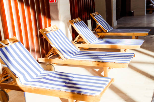 istock Sunlit public pool interior with chaise longues 958931100