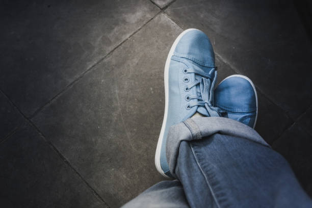 istock Feet jeans sneakers floor 958931494