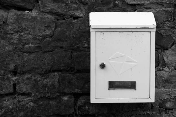 istock White metal mailbox on a brick wall. Old brick wall. Mailbox covered with dust and dirt. 958936402
