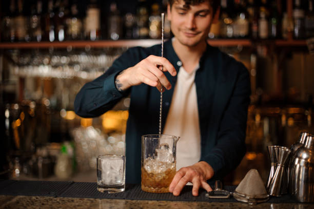 istock Brunet bartender stirring an alcoholic drink in the glass with ice 958937776