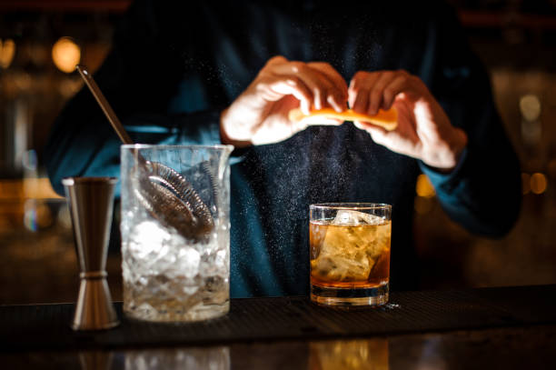 istock Brunet bartender adding an orange juice to the cocktail 958937886