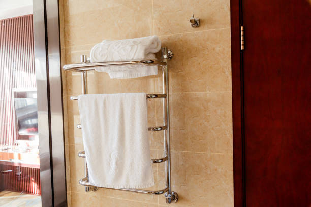 istock Modern heated towel rail on tiled bathroom wall. 958940012