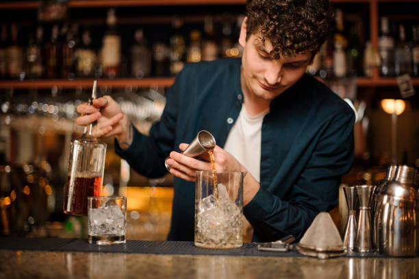 istock Brunet bartender adding an alcoholic drink into the glass with ice 958940014