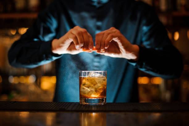 Brunet bartender adding a fresh orange citron to the cocktail