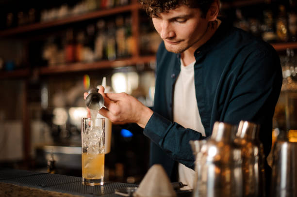 barista brunet versando una bevanda alcolica nel bicchiere - still shot foto e immagini stock