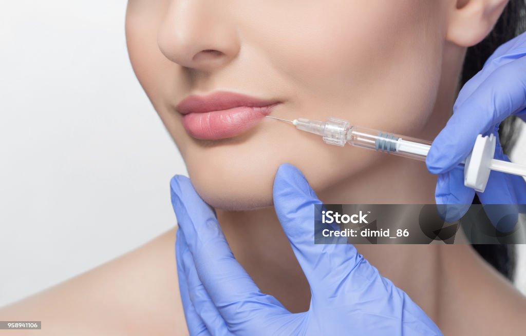 The doctor cosmetologist makes Lip augmentation procedure of a beautiful woman in a beauty salon. The doctor cosmetologist makes Lip augmentation procedure of a beautiful woman in a beauty salon.Cosmetology skin care. Human Lips Stock Photo