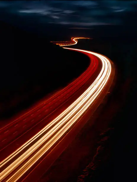 LONG EXPOSURE PHOTOGRAPH OF VEHICLE LIGHT TRAILS ON MOTORWAY AT NIGHT