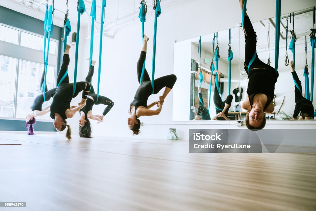 Women Exercising Together in Aerial Yoga Studio A group of friends enjoy a workout together in a brightly lit aerial yoga studio.  A relaxing way to unwind and exercise in community. Aerial Yoga Stock Photo