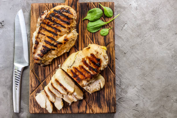 filetes de pollo a la parrilla sobre tabla para cortar madera - skinless chicken breast fotografías e imágenes de stock