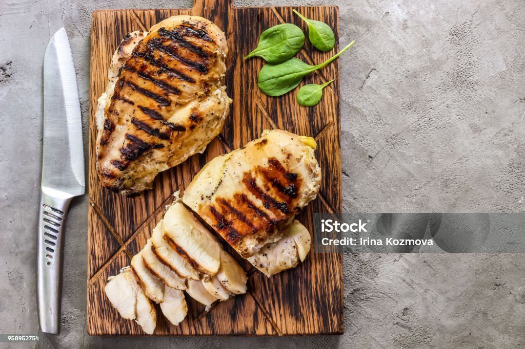 grilled chicken fillets on wooden cutting board grilled chicken fillets on wooden cutting board prep with cooked quinoa and spinach for healthy food Chicken Meat Stock Photo