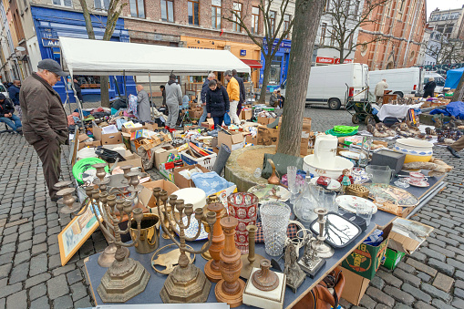Brussels, Belgium - April 3, 2018: Buyers on flea market with old metal candlesticks, bargains, antique stuff, vintage decor and retro utensils on April 3, 2018. More than 1,200,000 people lives in Brussels