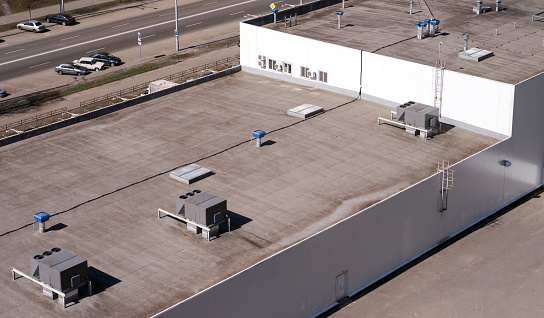 Roof of a commercial building with a external units of the commercial air conditioning and ventilation systems.