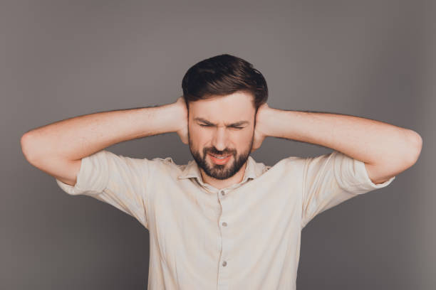 istock Sad overworked man with headache covering ears from noise 958965882