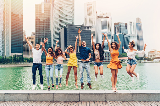 Group of young people jumping outdoors at cityscape background