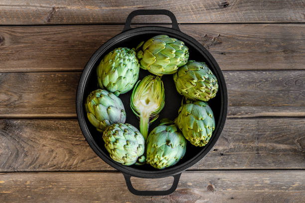 Artichoke in a pan on wooden table stock photo