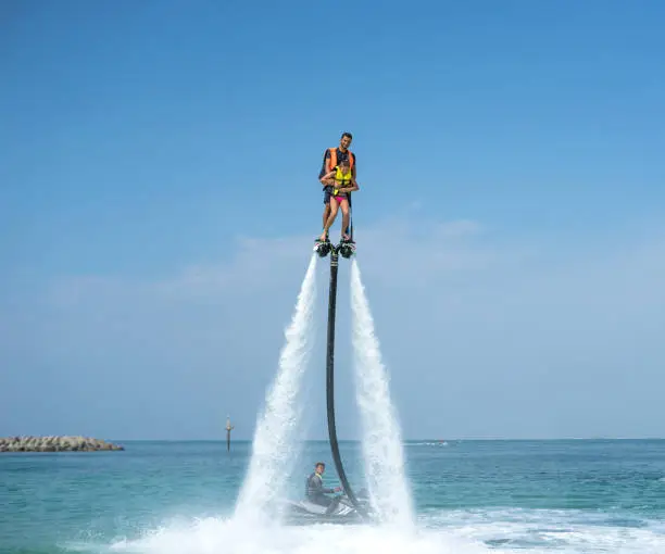 Photo of Father and his daughter posing at new flyboard at tropical beach. Positive human emotions, feelings, joy. Funny cute child making vacations and enjoying summer.